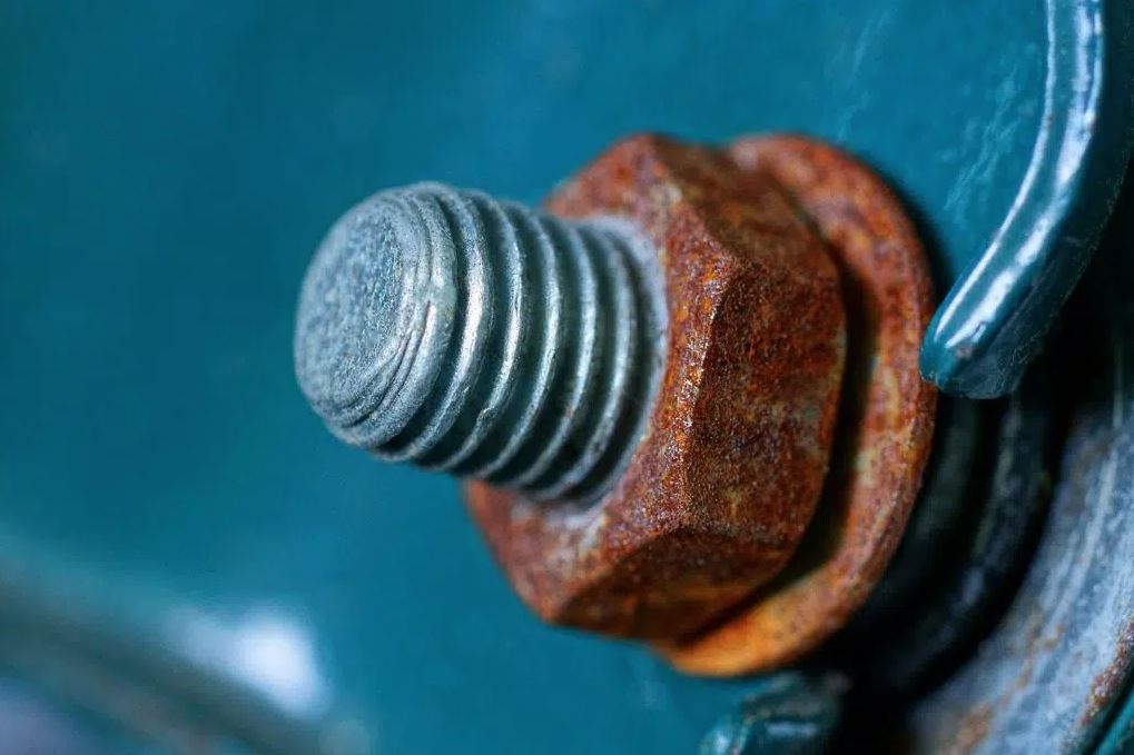 Dimly lit gallery space with suspended rusted panels emitting low sound waves